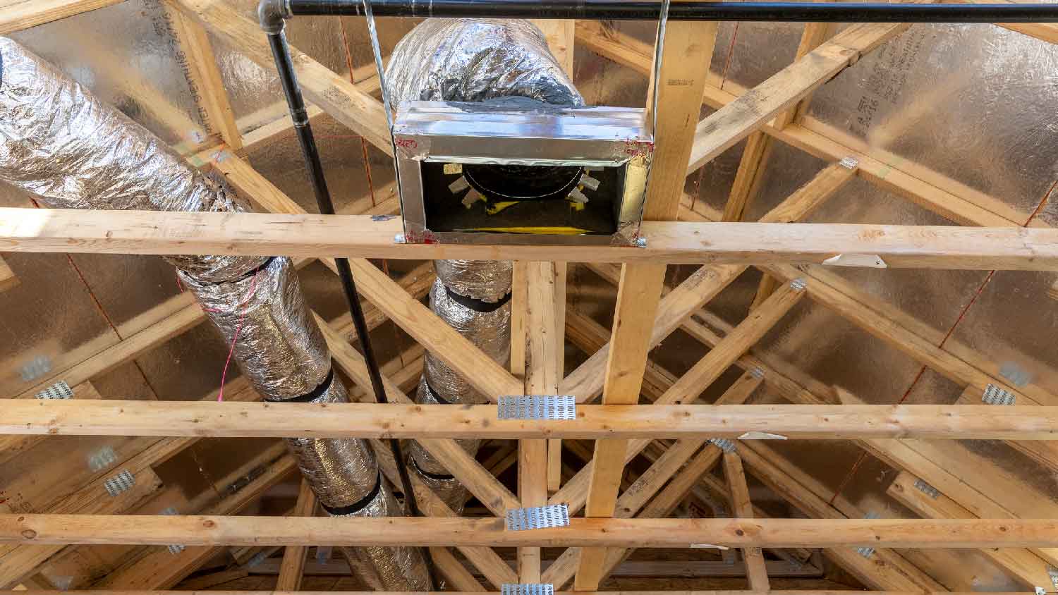 Angled wooden beams on attic with ductwork and air vent