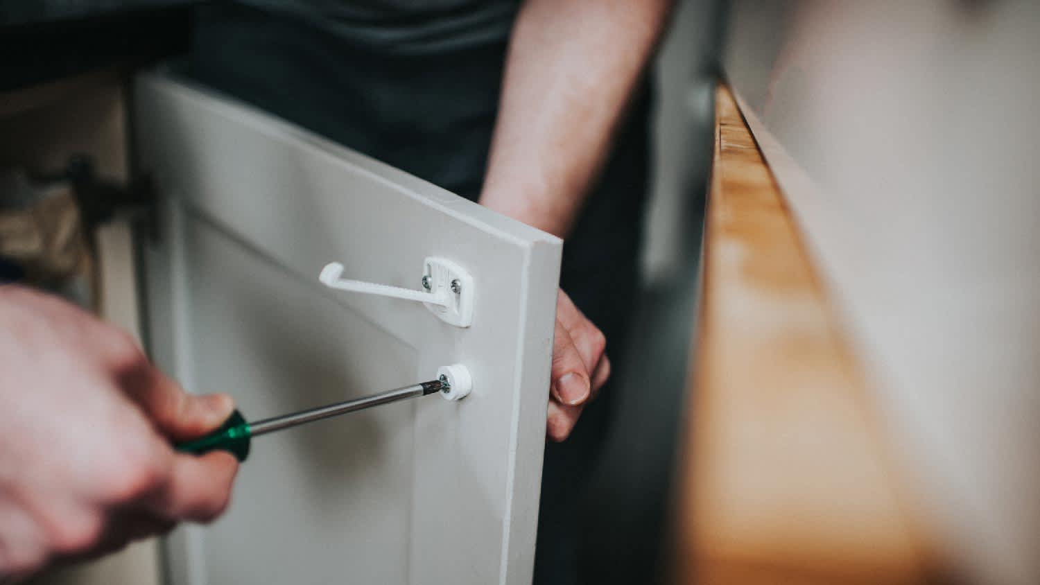 A man removing a cabinet handle