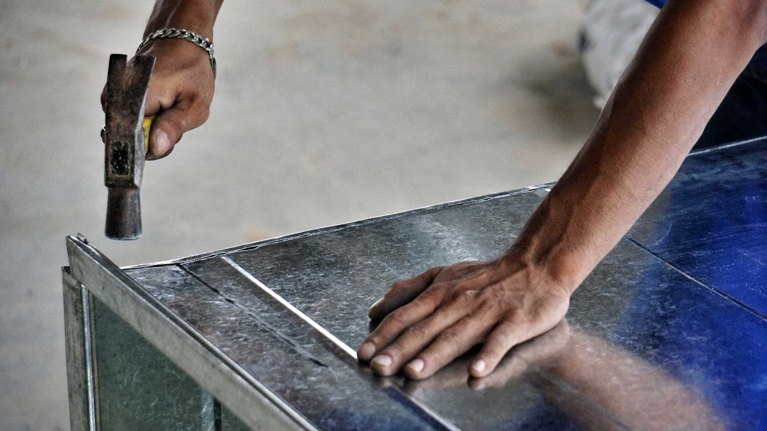 A person connecting air ducts with a hammer
