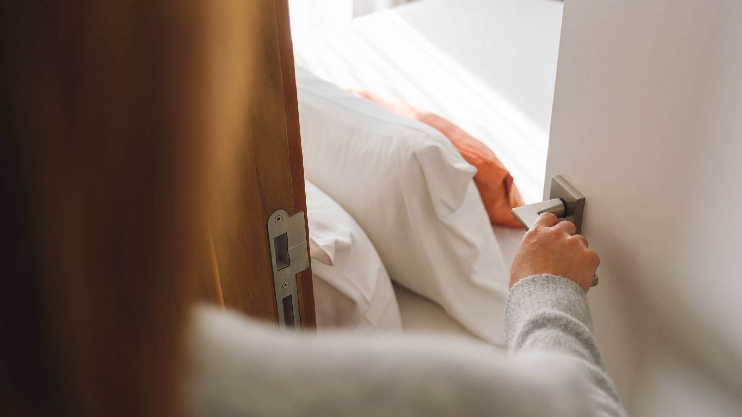 A woman opening the door to a bedroom