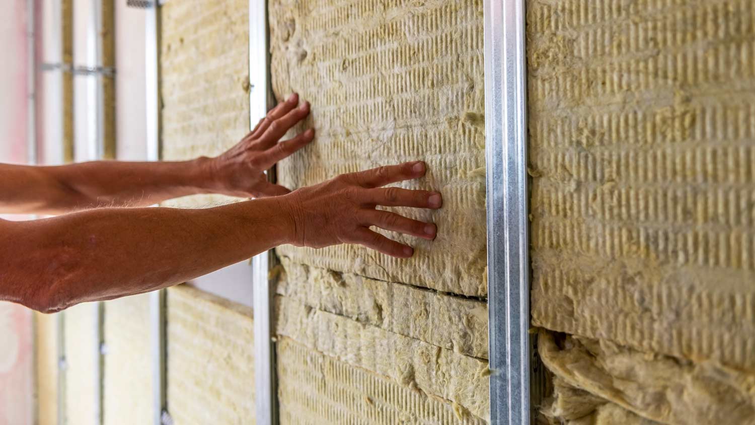 man insulating room with mineral wool