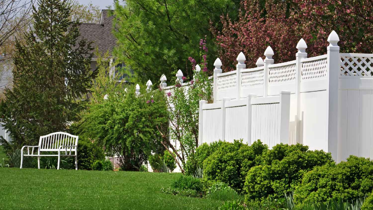 A white vinyl fence behind a beautiful garden