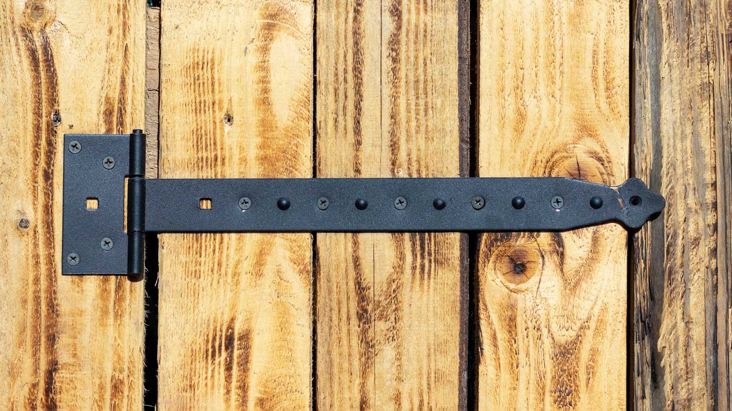 Big black hinge on door made of wooden boards