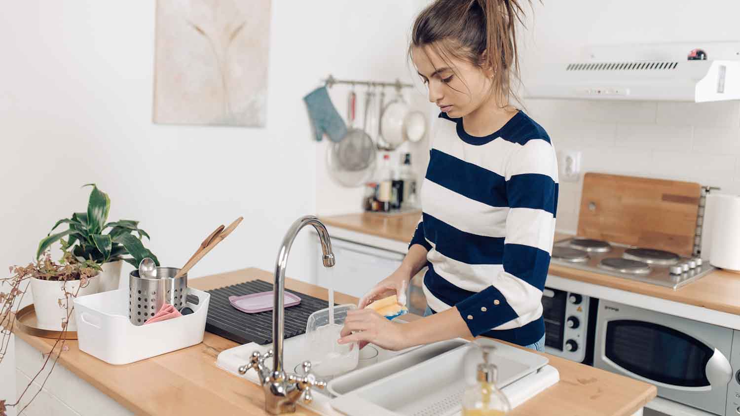 Teenage girl washing dishes by hand