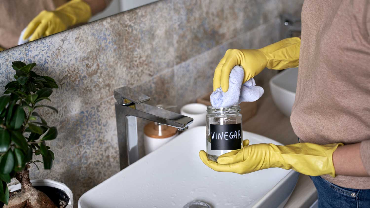 A woman cleaning the bathroom sink with vinegar