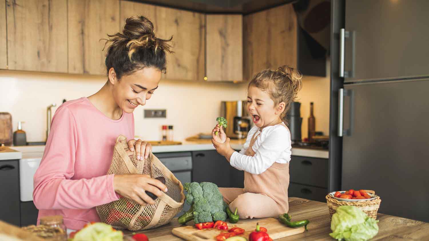 Daughter helping mom prep vegetables in the kitchen