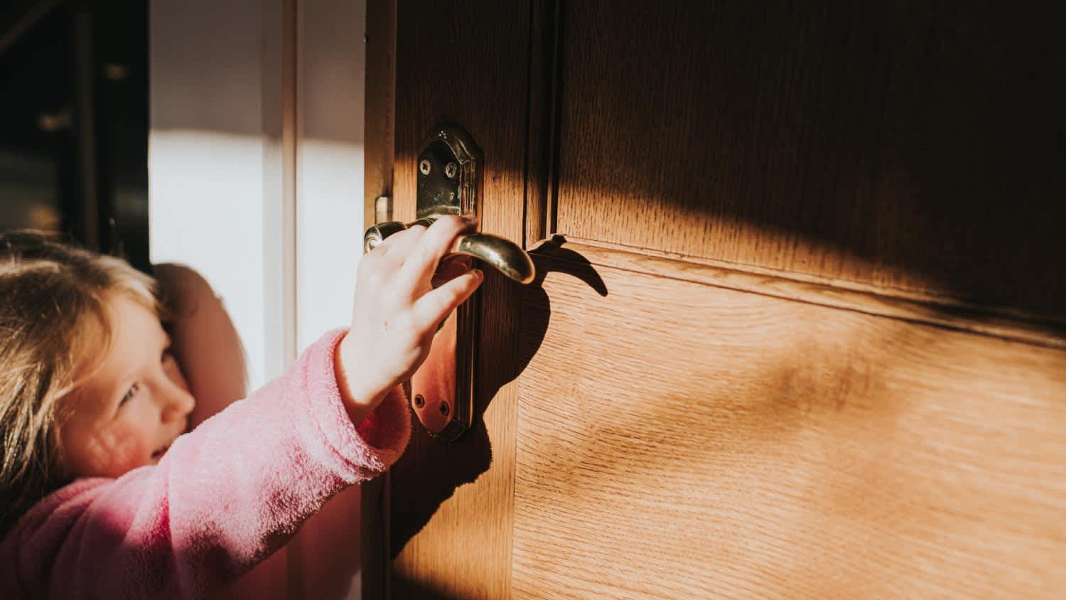 A little girl attempts to open a door