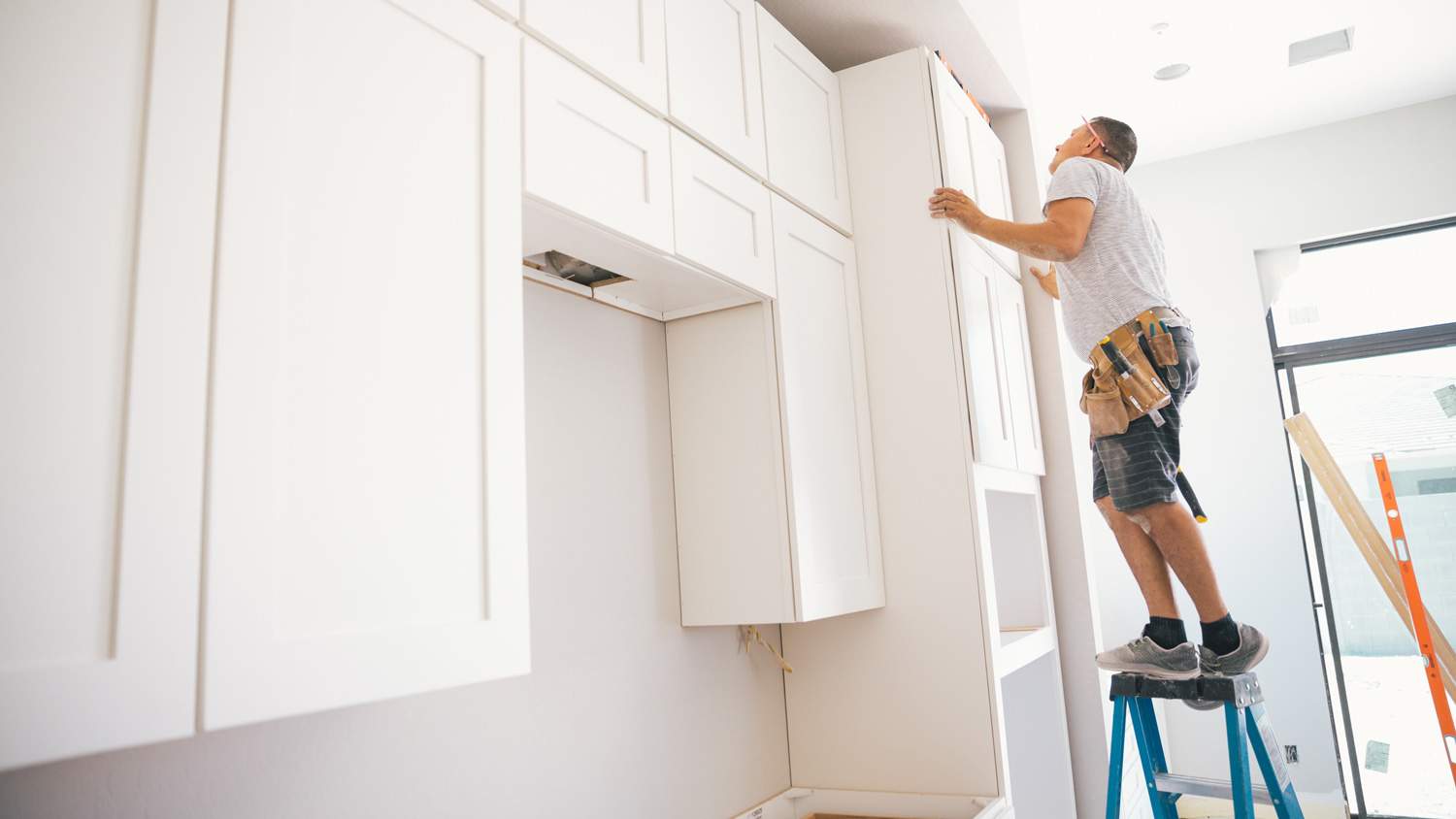 A professional installing new kitchen cabinets