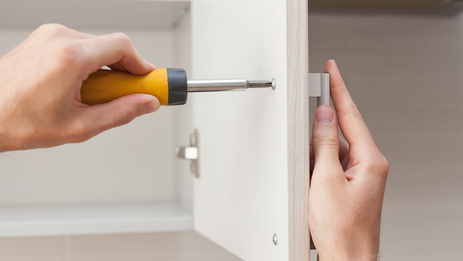 man installing handle on kitchen cabinet