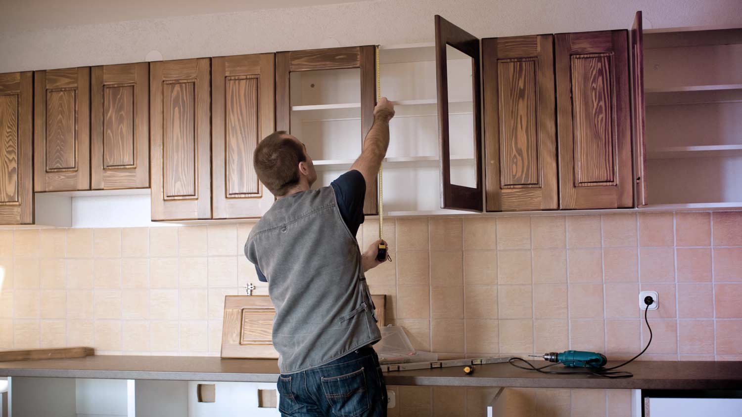man measuring  kitchen cabinets