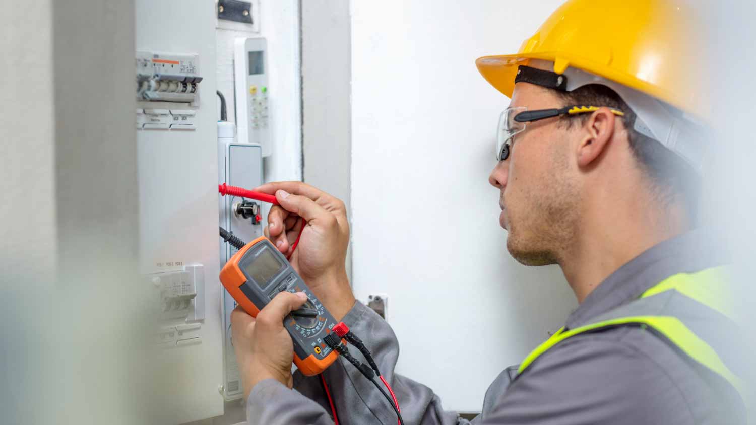 Electrician working with voltmeter at fuse box