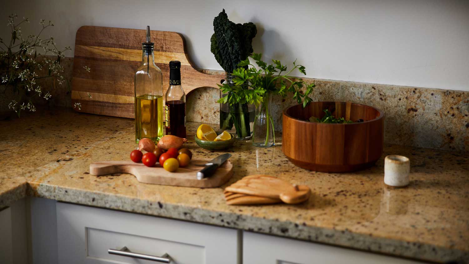 A brown granite countertop with a cutting board and tomatoes on it