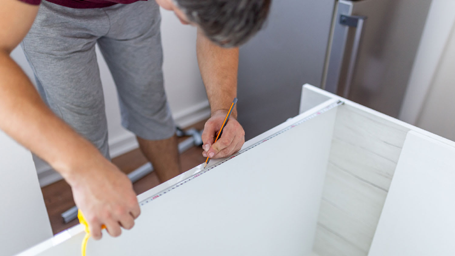 A man measuring a cabinet