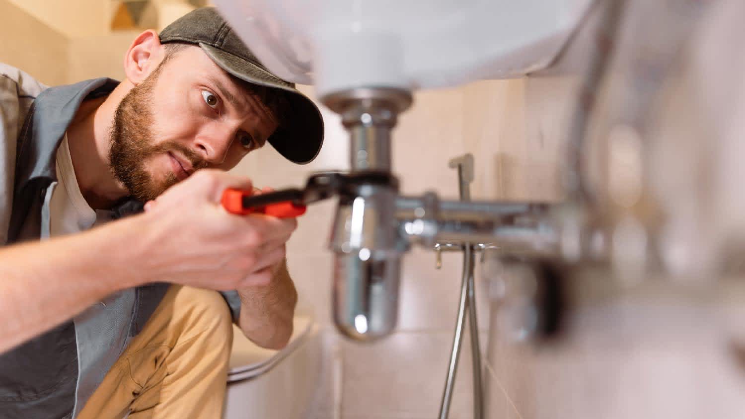 A man repairing leaking bathroom pipes
