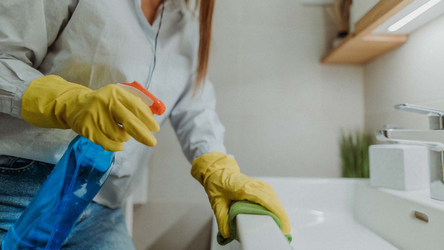 A woman spraying a solution in a bathroom