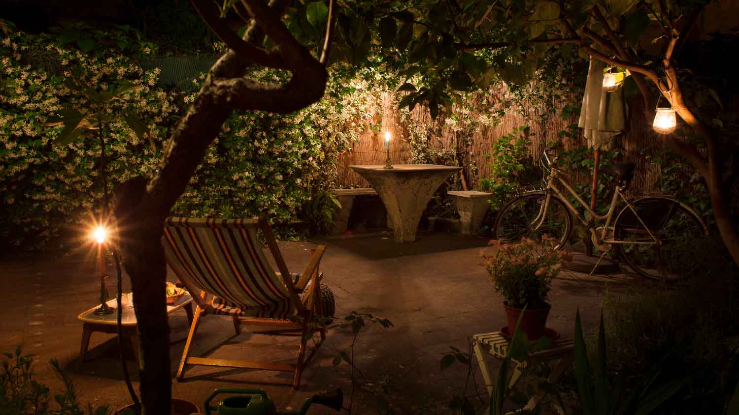 A candlelit backyard with a jasmine in full bloom