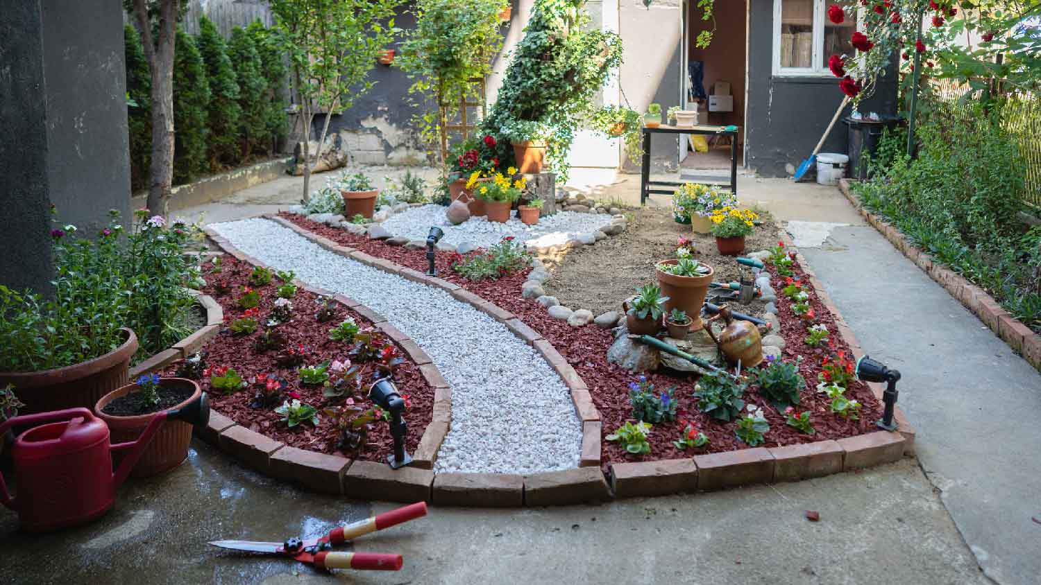A small garden with flower beds with brick edging