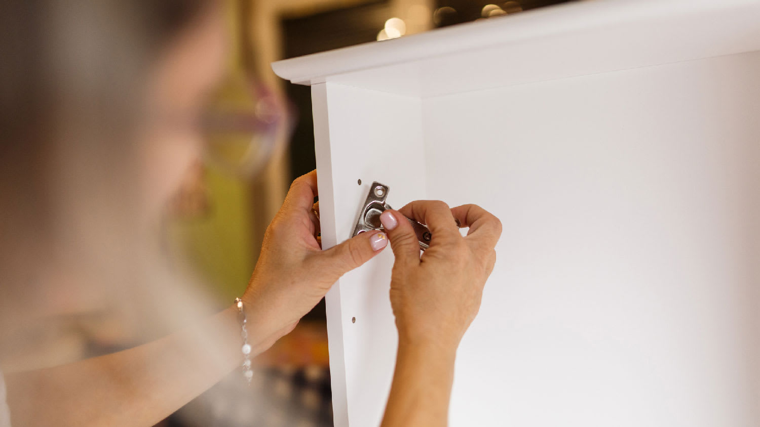 A woman installing a cabinet hinge