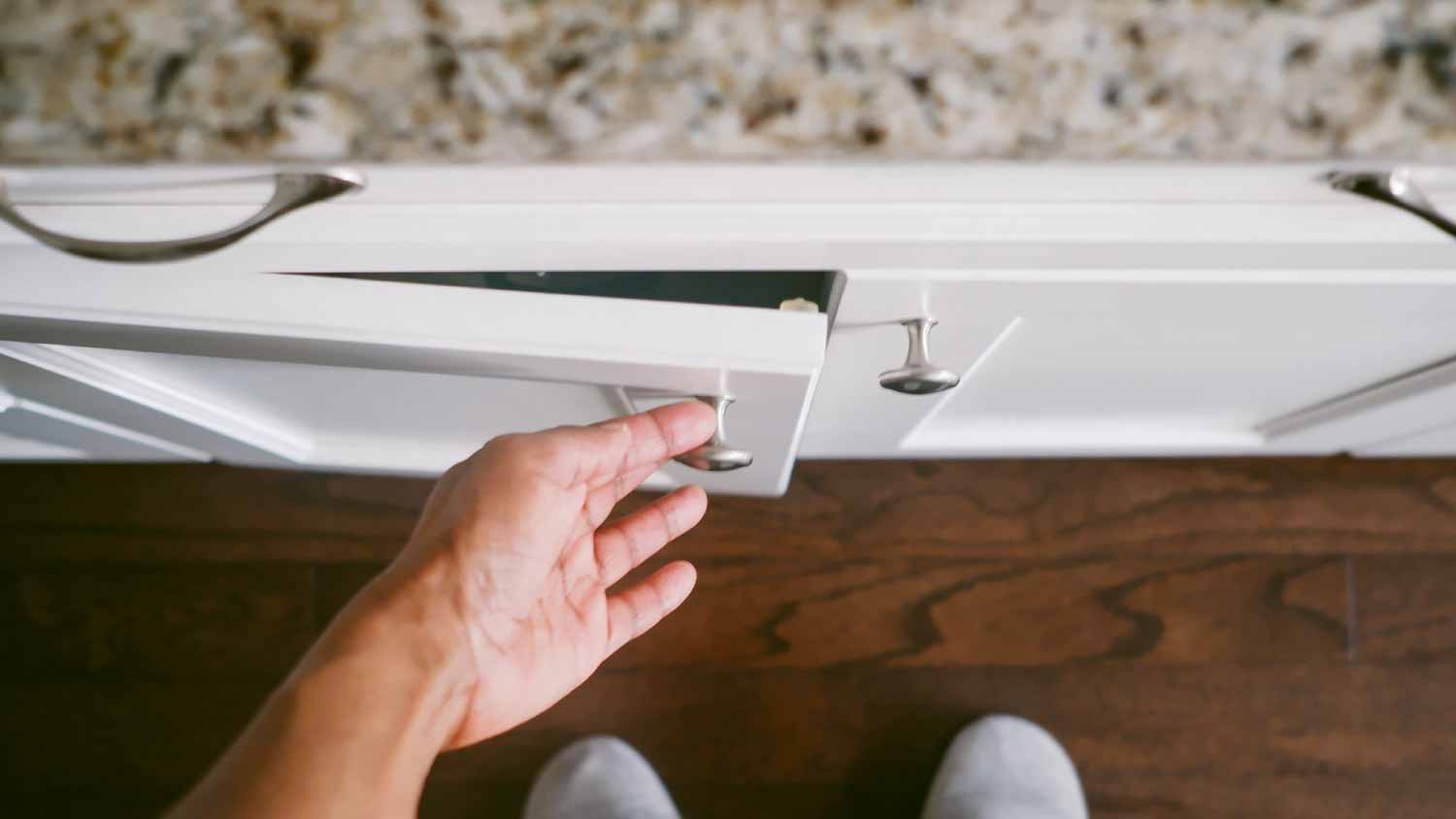 woman opening white kitchen cabinets