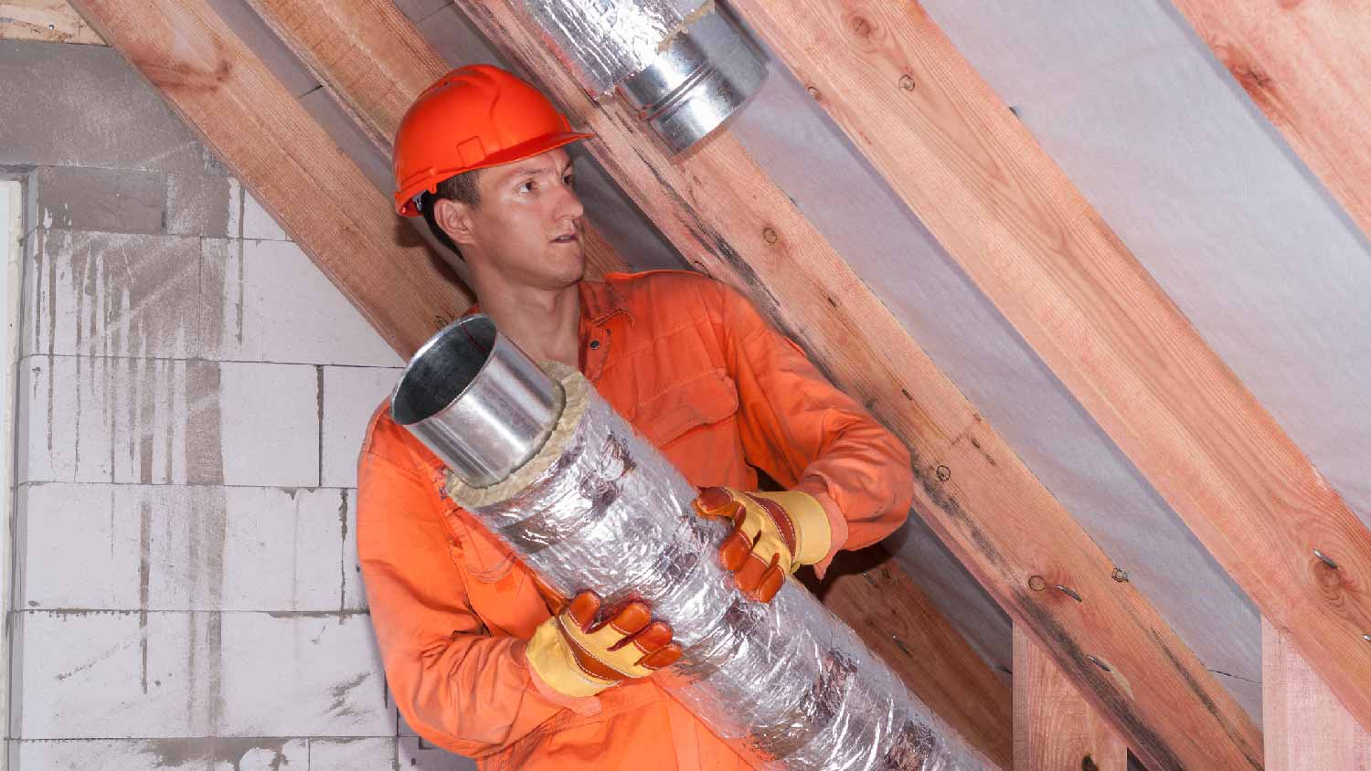 A professional insulating ductwork in an attic