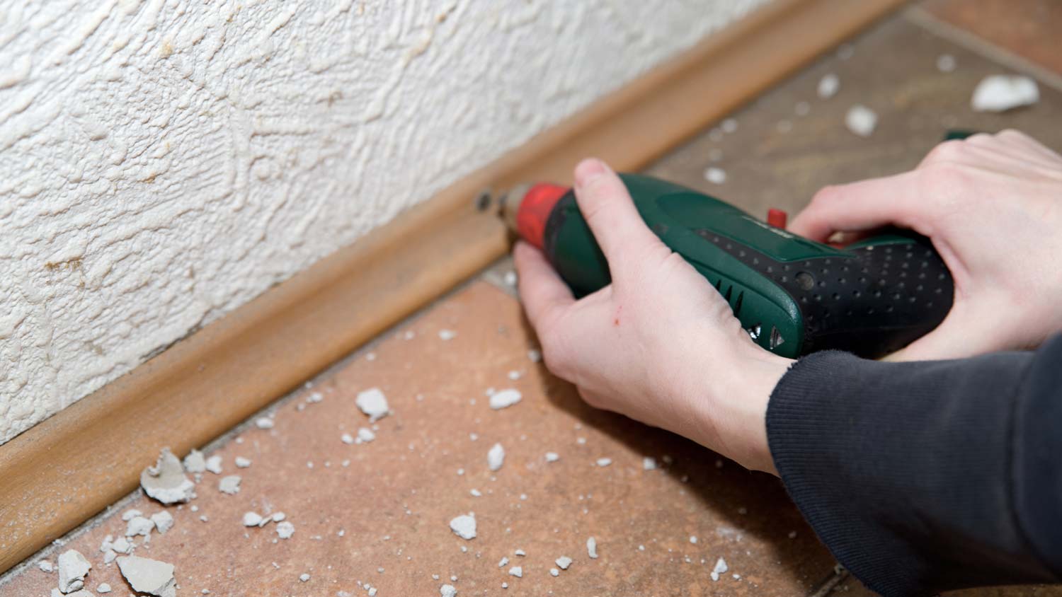 man using drill to remove baseboard
