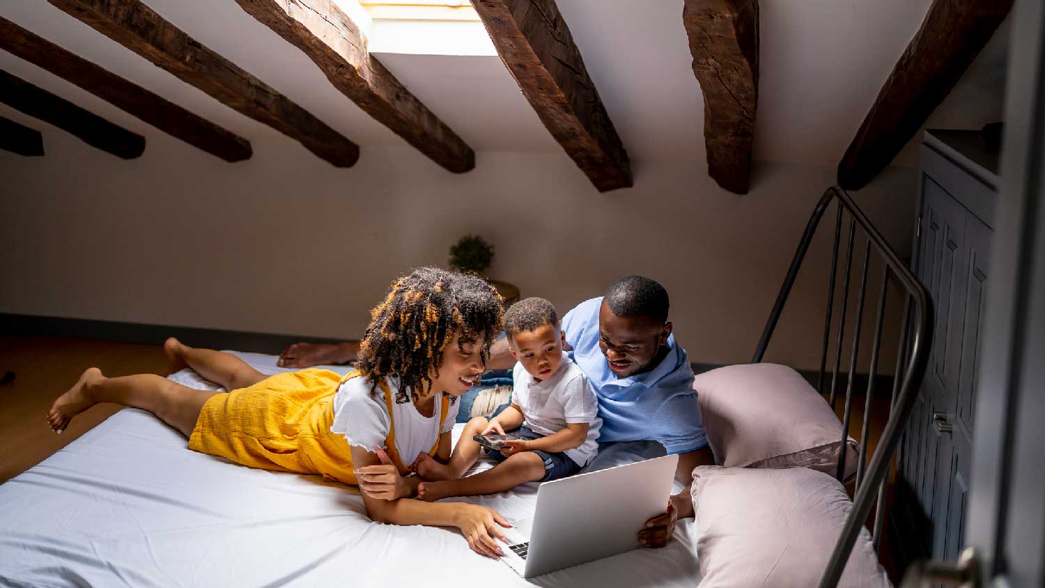 A family using a laptop on a bed in an attic
