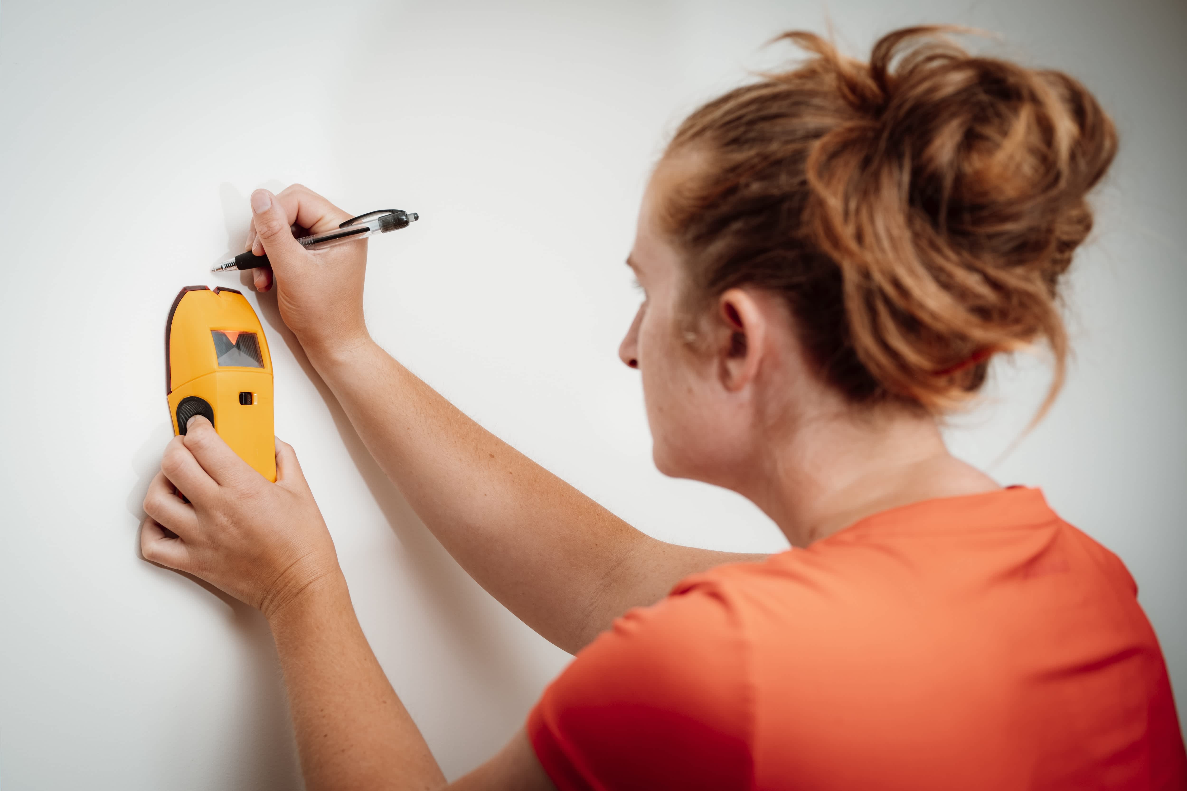 woman using a stud finder on drywall