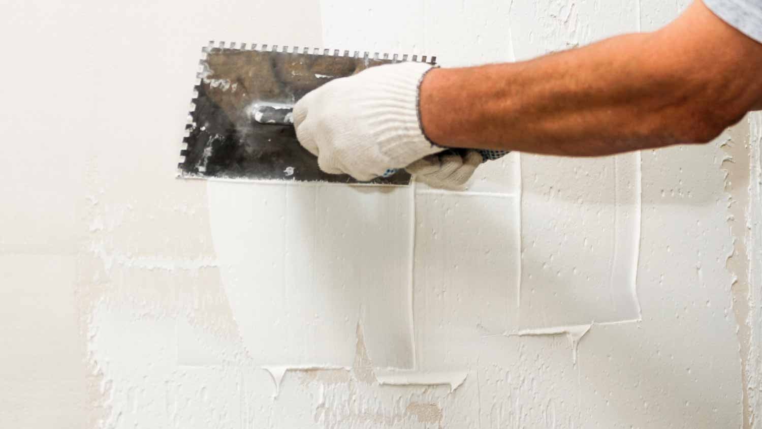 Man plastering a wall with a comb