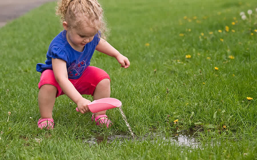 Child plays with a toy scoop in the yard