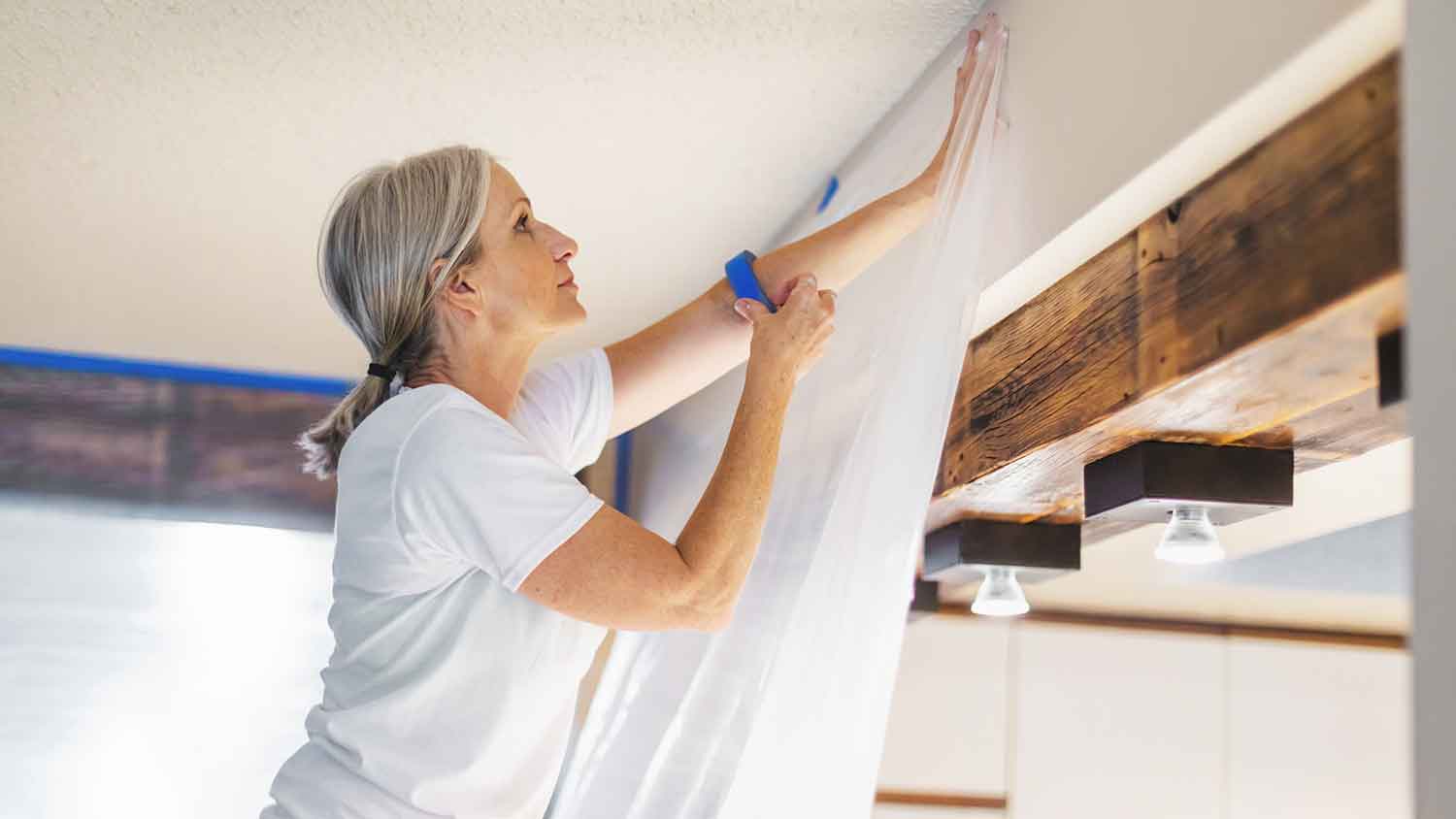Woman using tape and plastic for painting preparation