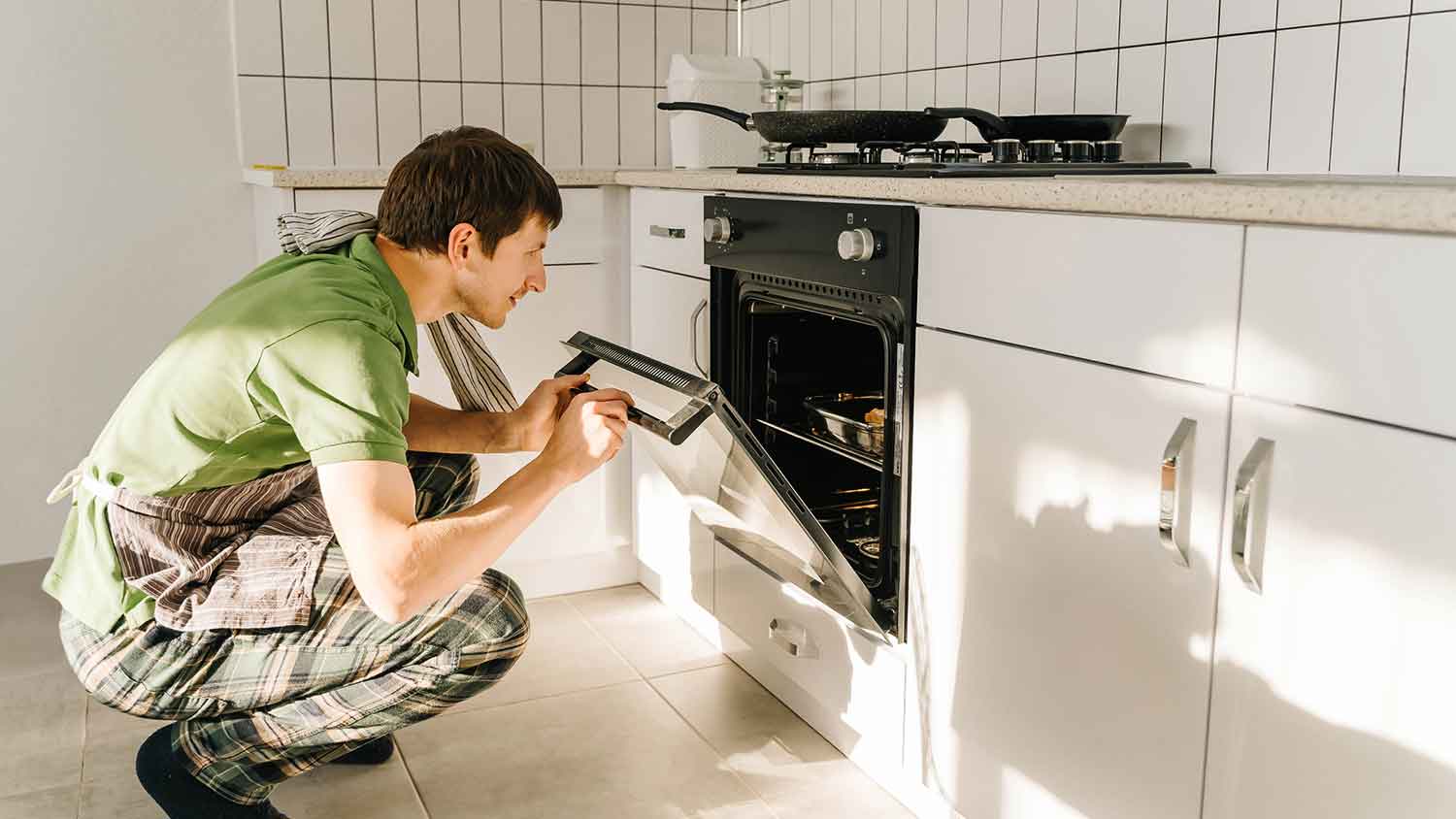 Man using oven at home to make dinner