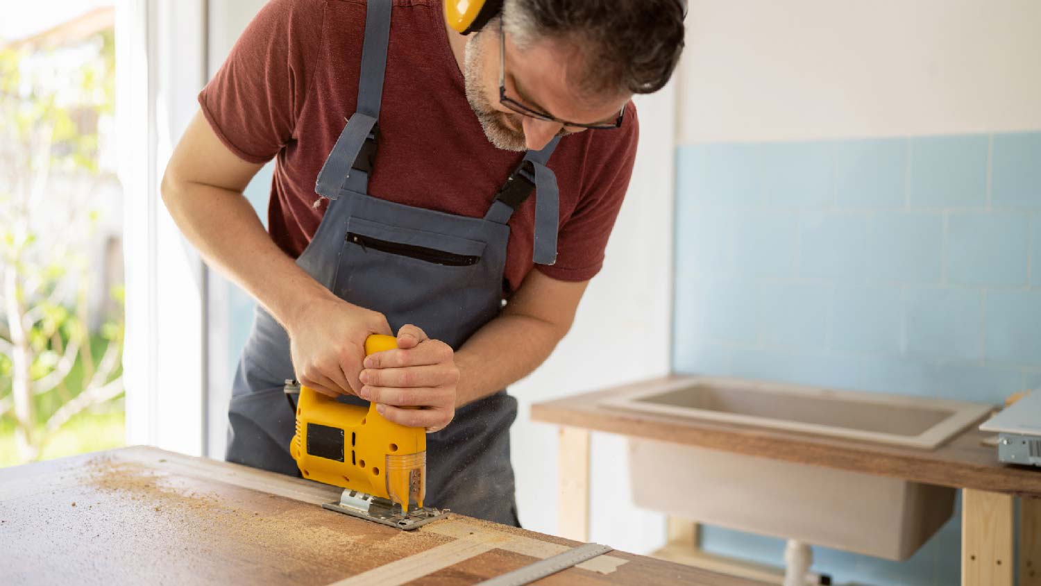 A man cutting a butcher block countertop