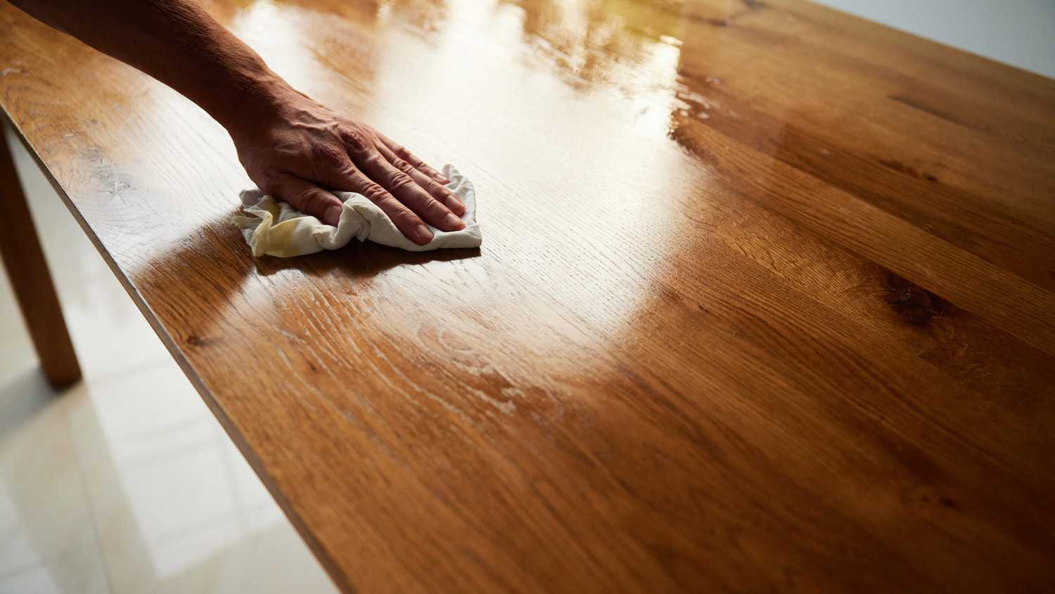 Closeup of man Oiling wooden oak table with cloth