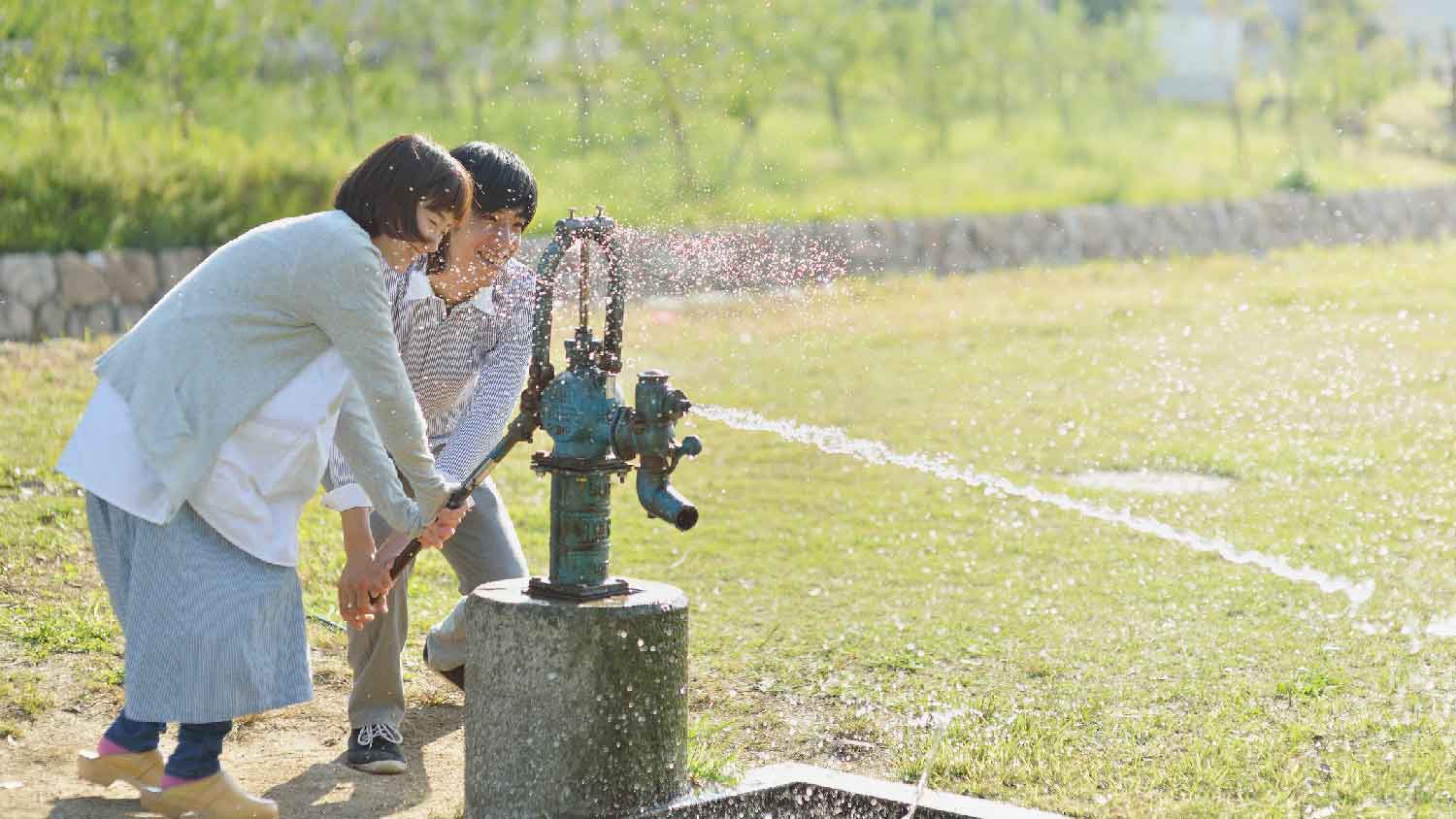 A couple pumping water from well