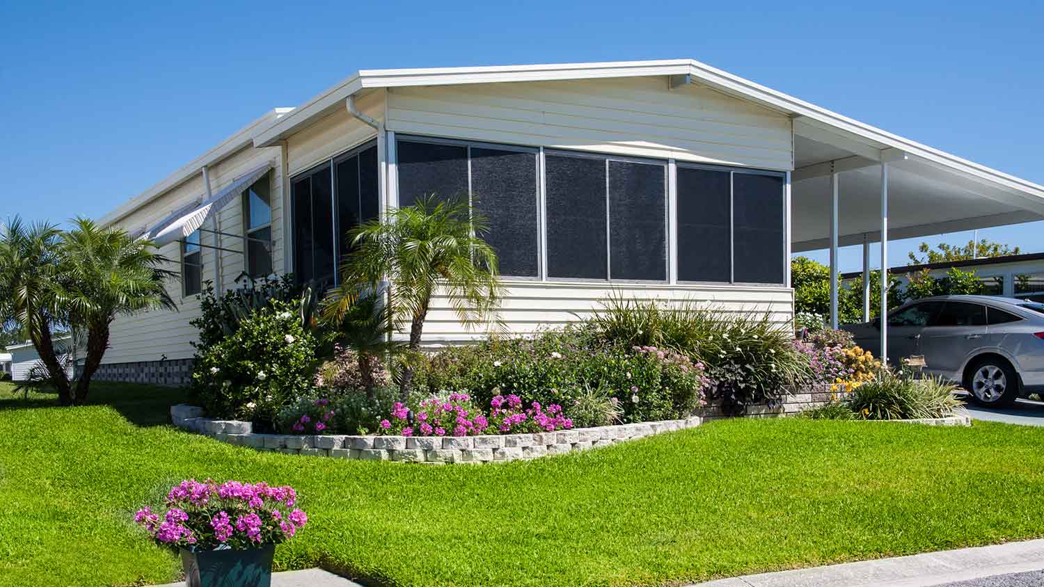 Mobile home with well-maintained front yard and palm trees