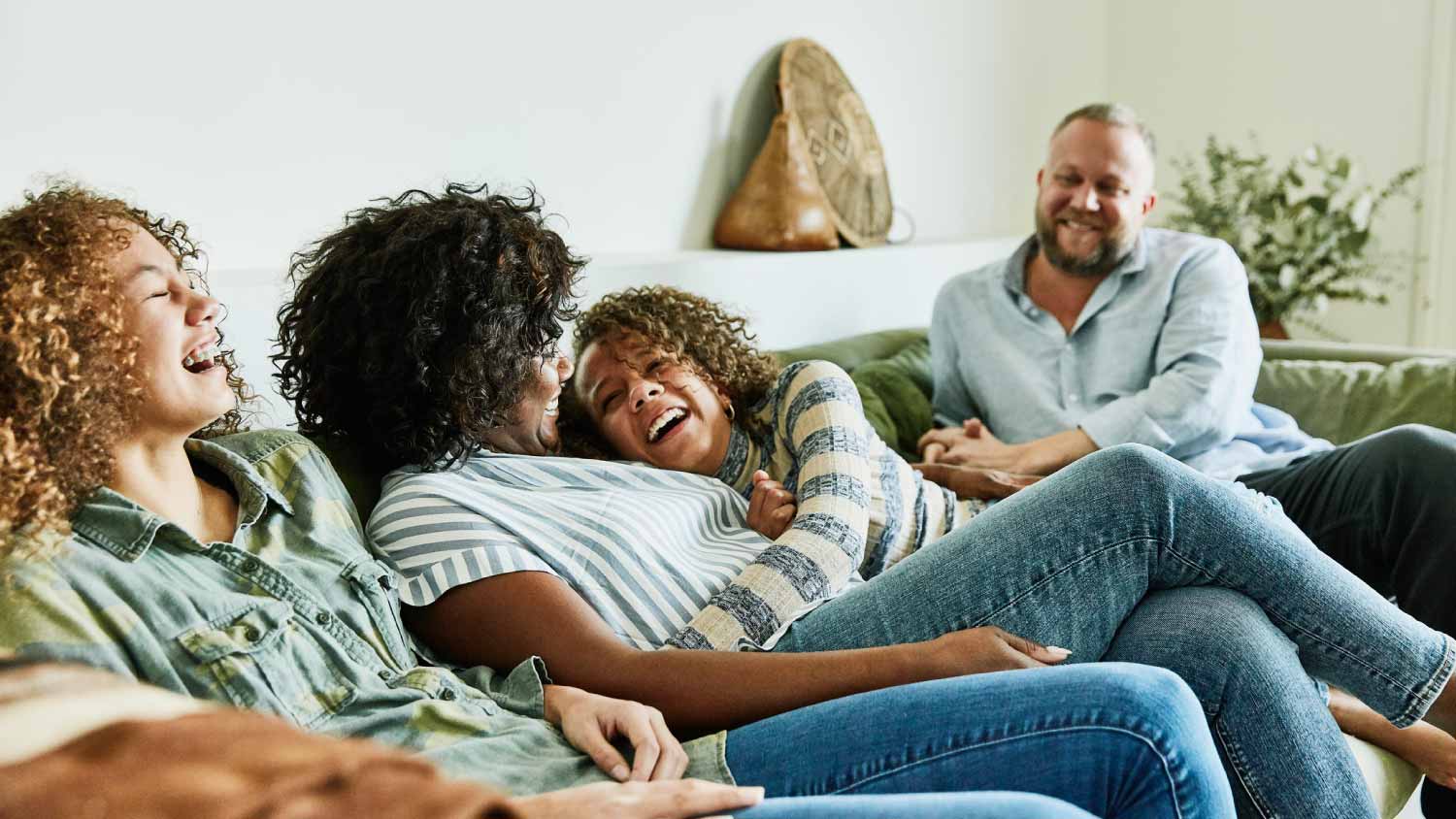 Family laughing while sitting on couch