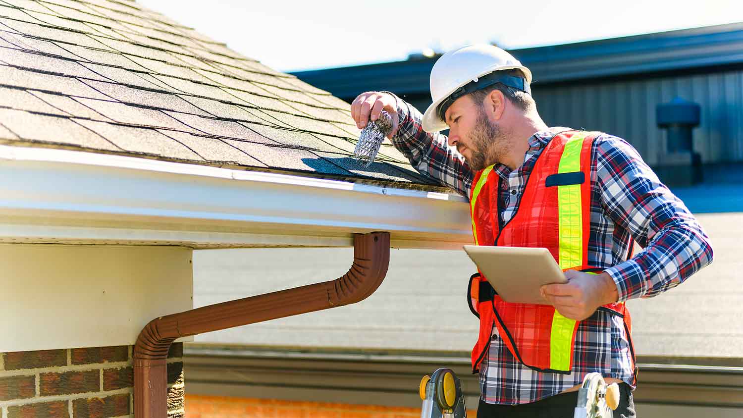Home inspector wearing helmet checking gutters