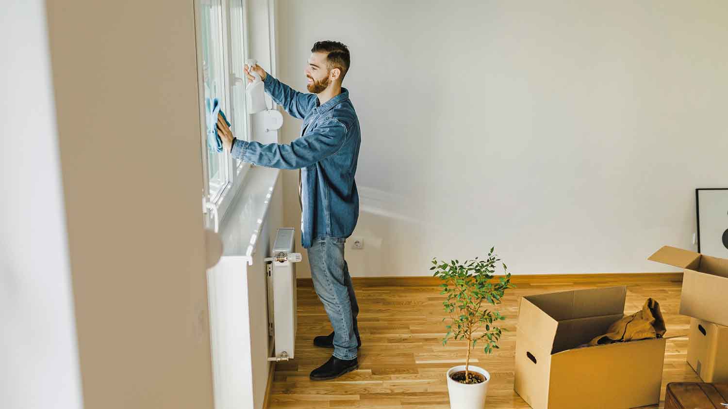 Man cleaning windows in his apartment before moving-out