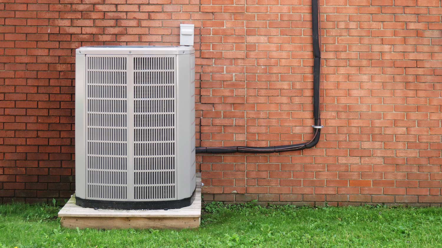 A HVAC system in front of a brick wall
