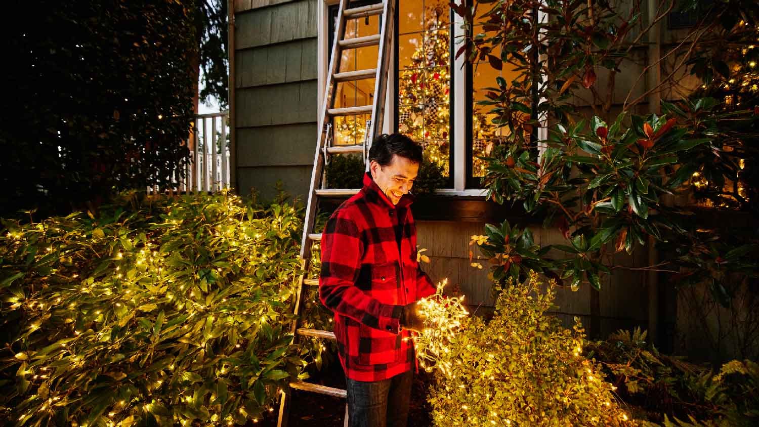 A man placing Christmas lights on the outdoor of his house