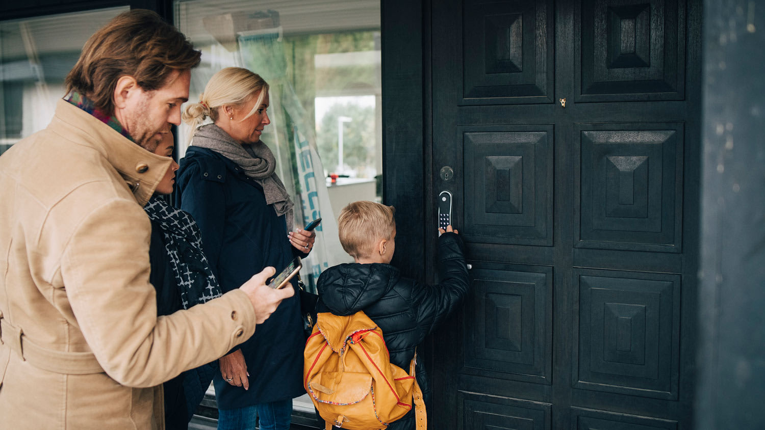 Son unlocks smart lock on door as family looks on