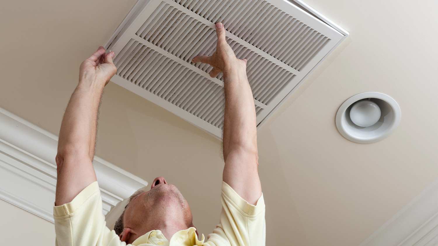 A man adjusting an air duct