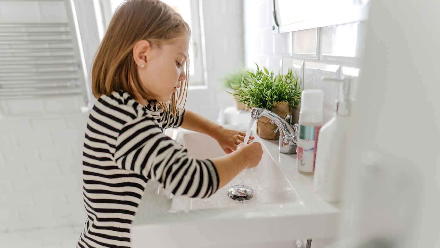 Little girl washing hands in the bathroom