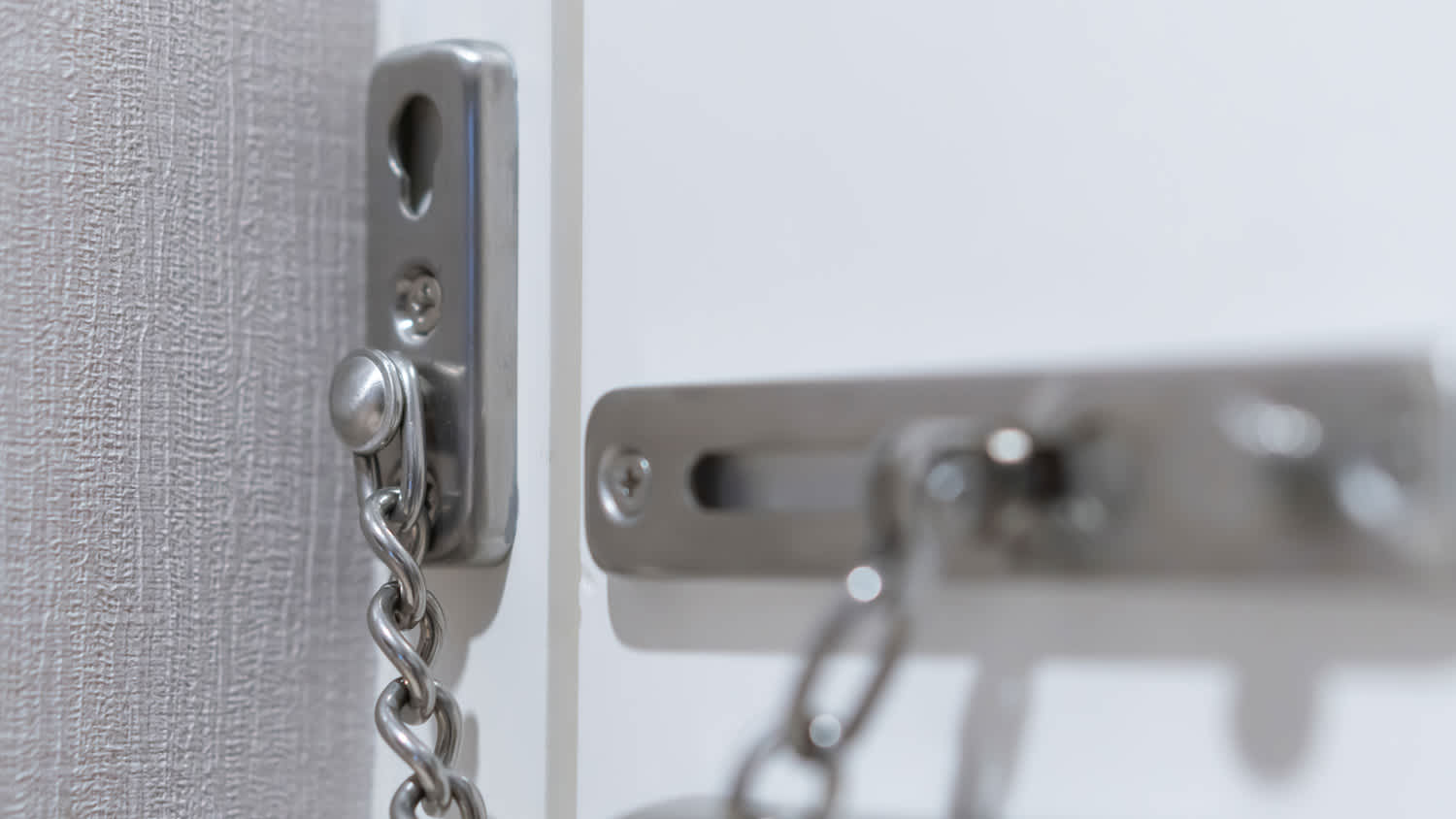 A metal chain lock behind a closed door