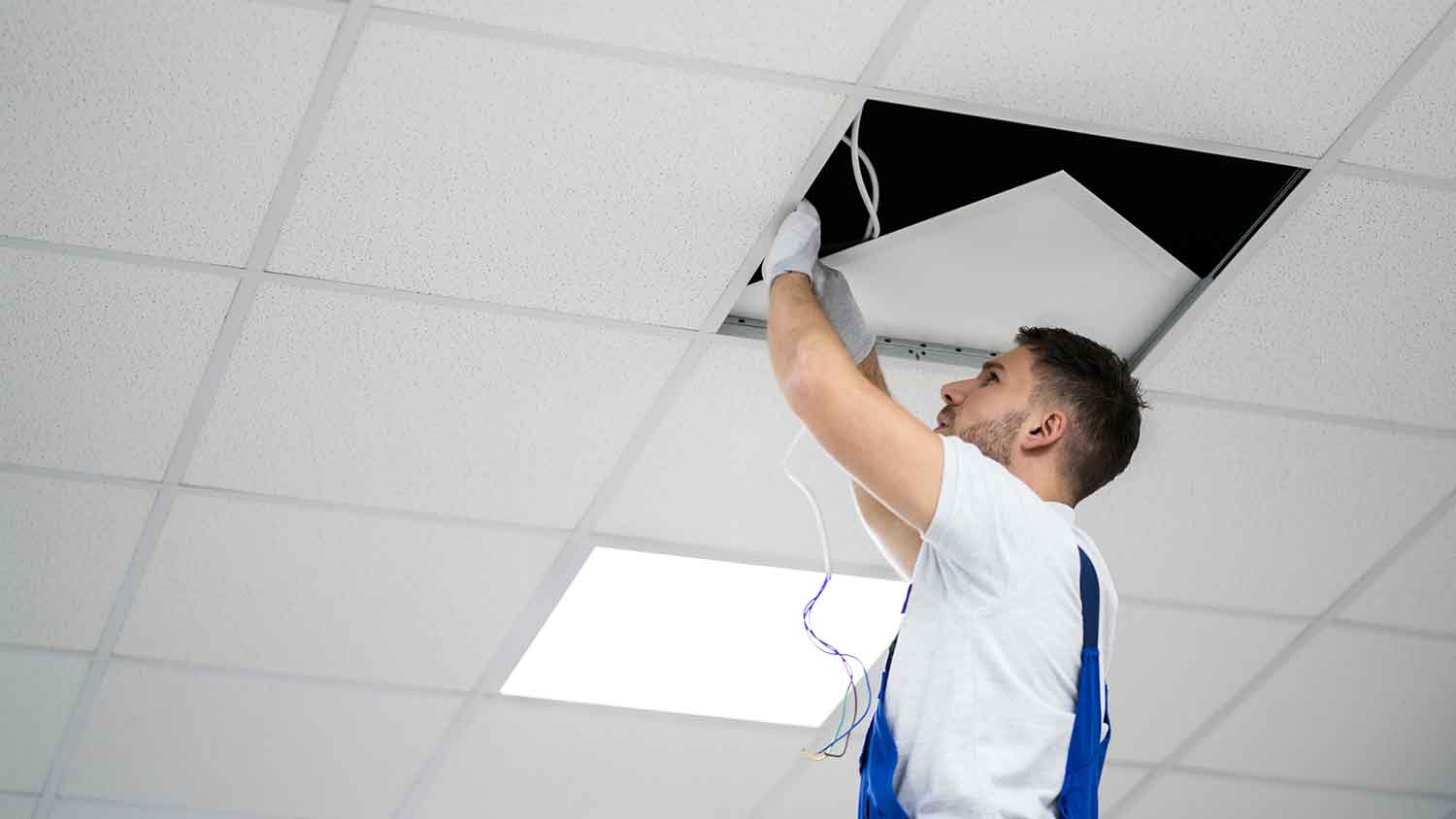 Electrician installing lights in a drop ceiling