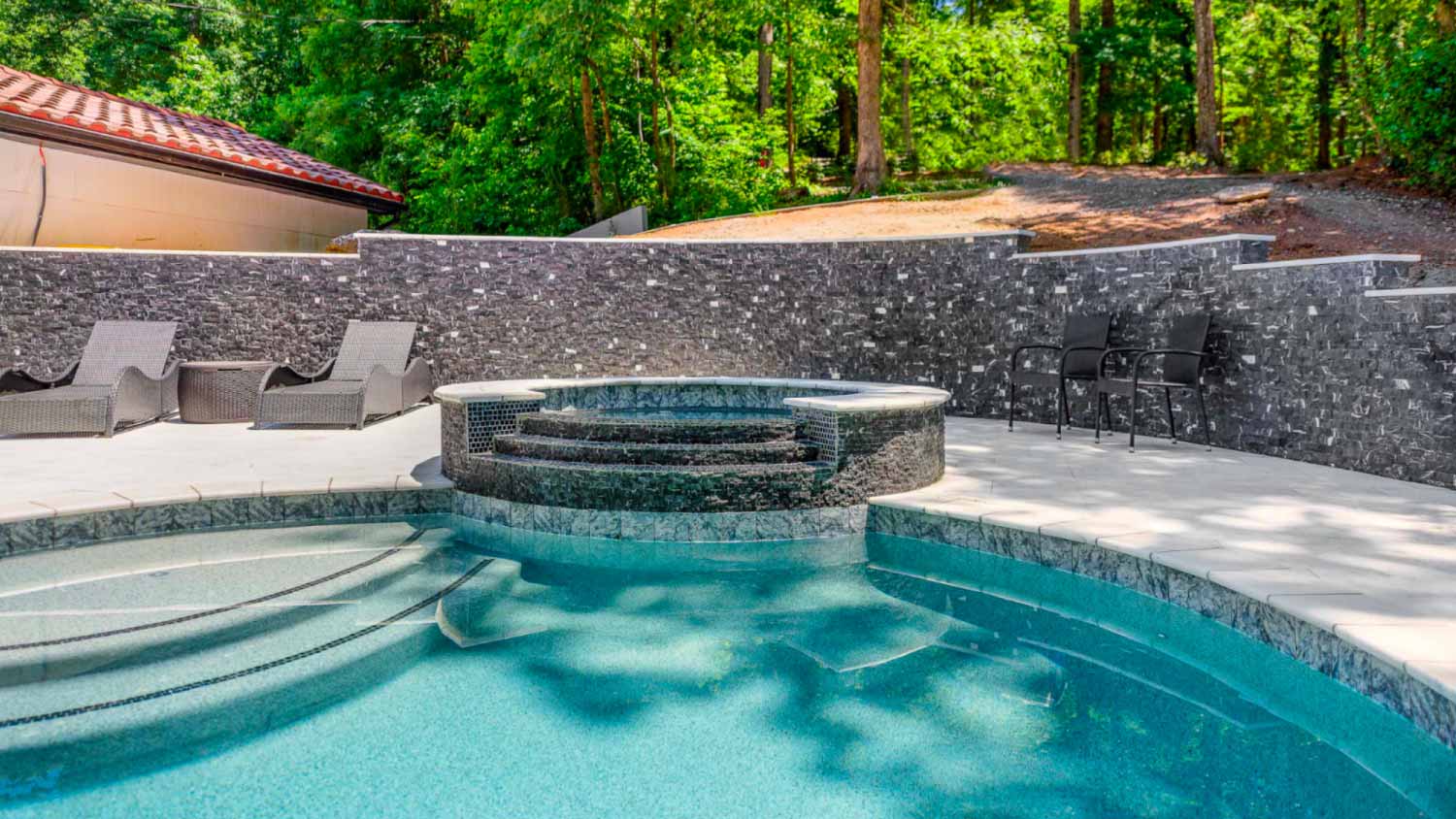 A view of a backyard hot tub with a waterfall
