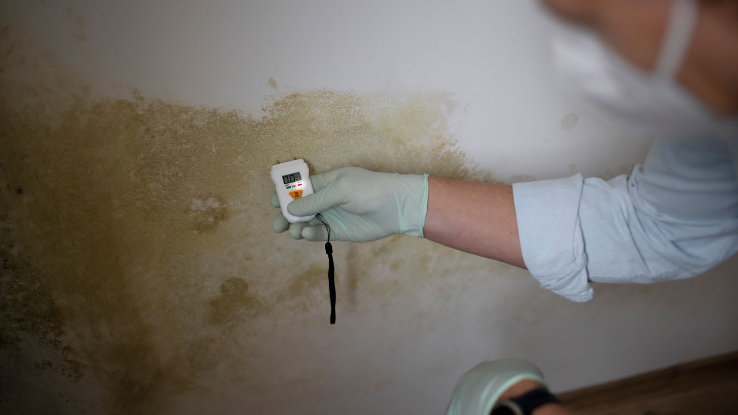 man measuring moisture levels on wall