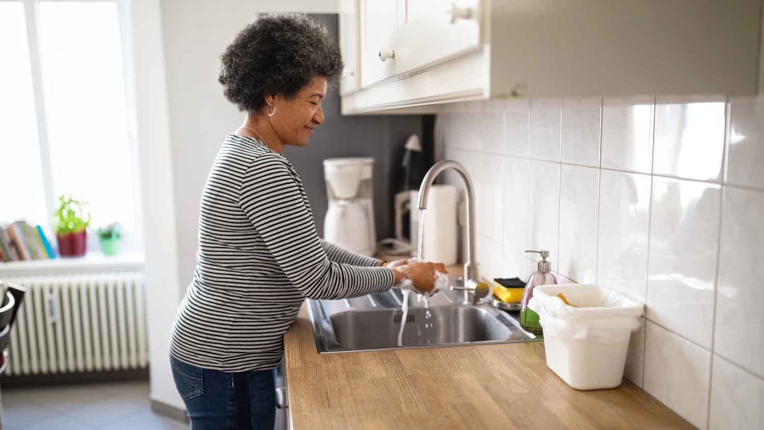 Woman using kitchen sink to wash her hands