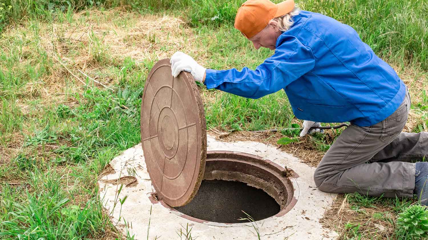 Man removing septic tank cover to inspect the tank