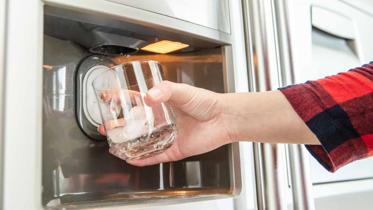 Woman using refrigerator to make ice cubes